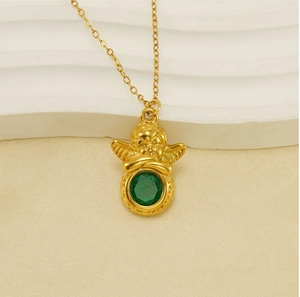 Detailopname van de gouden engel hanger met groene zirkoon op een getextureerde stof