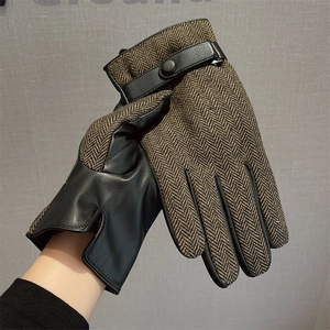 Detailed close-up of men's winter gloves featuring brown herringbone fabric and black leather