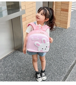 Toddler girl wearing a pink hard shell backpack with a 3D cartoon bunny design and dots
