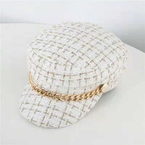 Detail view of white tweed newsboy hat with gold chain decor and metallic buttons