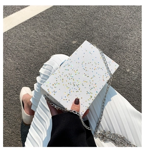 Close-up of a white box bag with colorful star patterns and a silver chain strap