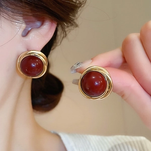 Detail of vintage round burgundy pearl stud earrings with golden spiral wire wrap detail