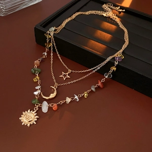 Detail of layered gold necklace with sun, moon, star pendants and colorful gemstones