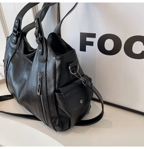 Detail of black faux leather tote bag with silver zippers, side pockets and shoulder strap