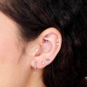 Close-up of S925 silver fringe butterfly ear piercings with opal and blue gemstones