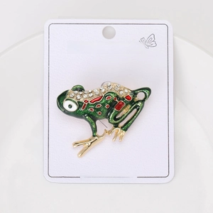 Detail of green enamel frog brooch with crystal rhinestones on a white card display
