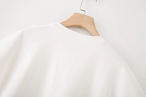 Gros plan du col rond et des détails en dentelle sur ce t-shirt blanc en maille tricotée