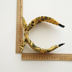 Ethnic style yellow paisley print knot headband with size measurement on white background