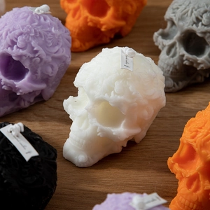 Halloween skull scented candles with carved floral patterns in various colors on wood
