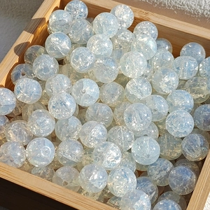 Macro shot of 10mm iridescent white glass beads with gold foil effect in a wooden tray