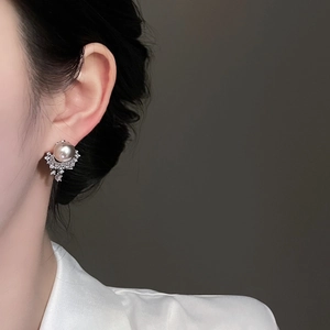 Detailed close-up of a pearl earring with sparkling crystals on a model's earlobe