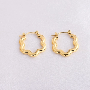 Close-up of golden petal-shaped wave hoop earrings with clear buckle details on fabric
