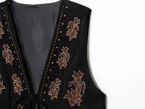Détail de broderie florale dorée sur gilet en daim noir avec motifs ethniques chic