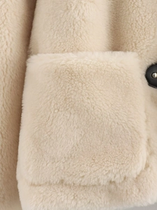 Gros plan sur la texture polaire beige et la boucle noire d'une veste d'hiver
