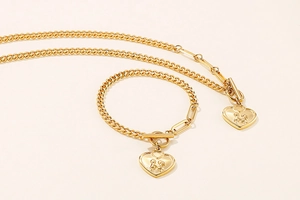 Detail of gold titanium heart necklace and bracelet set with human figure engravings