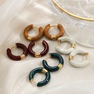 Detail of round enamel hoop earrings in brown, red, green and cream on silk fabric