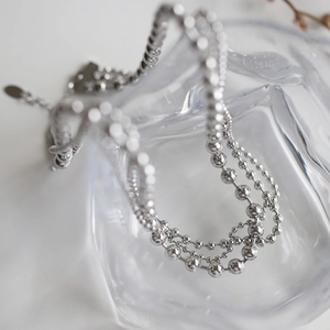 Detailed macro view of multi-layered silver bead chain necklace with polished finish