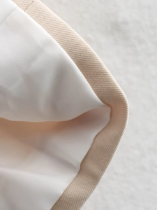Close-up of beige twill fabric and smooth white satin lining on a loose-fit blazer