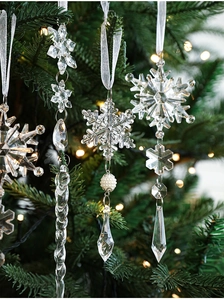 Close-up of clear acrylic snowflake and icicle ornaments hanging on a Christmas tree