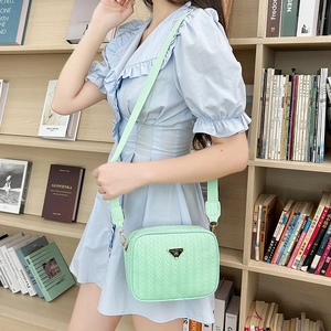 Mint green woven leather camera bag for women featuring a metal triangle plaque and strap