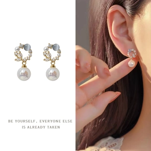 Detail of vintage French gold earrings with white pearls and grey cat eye stones