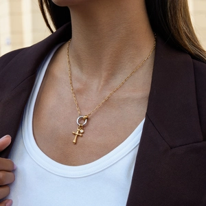 Close-up of golden stainless steel heart cross necklace with small gemstone on female model