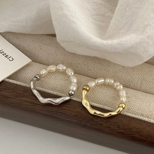 Primer plano de anillos ondulados en oro y plata con pequeñas perlas de agua dulce