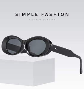 Detailed side view of stylish black oval sunglasses on a minimalist white geometric display