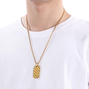 Close-up of a men's 18k gold-plated stainless steel bar pendant worn on a white T-shirt