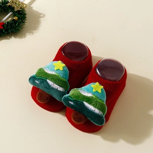 Close-up of red baby Christmas socks with green tree decor and knit texture