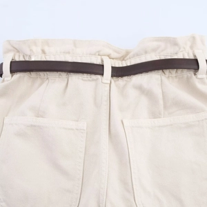 Dettaglio di pantaloncini in twill di cotone crema a vita alta con cintura marrone scuro