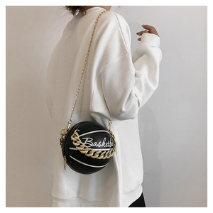 Close-up of a black basketball-shaped bag with a gold chain strap and white lettering
