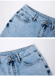 Détails de la ceinture en jean bleu clair avec bouton métallique et coutures précises