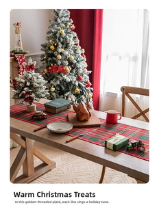Festive red and green plaid table runner with gold thread on a wooden dining table
