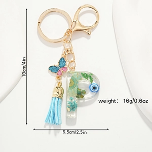 Detailed view of resin letter P keychain with blue evil eye, tassels, and size dimensions
