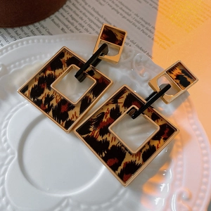 Macro detail of geometric leopard print earrings with gold frames on a vintage tray