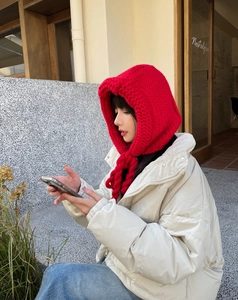 Détail de la cagoule tricotée rouge montrant la texture épaisse et les cache-oreilles