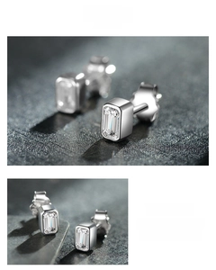 Macro shot of emerald cut zircon stud earrings in silver-tone bezel setting with high polish