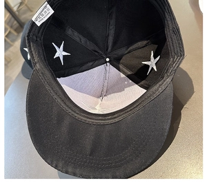 Détail intérieur d'une casquette noire avec broderie étoile et étiquette de matière