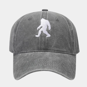 Detailed close-up of white Bigfoot embroidery on dark grey washed cotton baseball cap