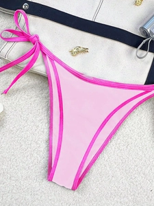 Detailed view of pink color-block bikini bottom with adjustable side ties on soft background
