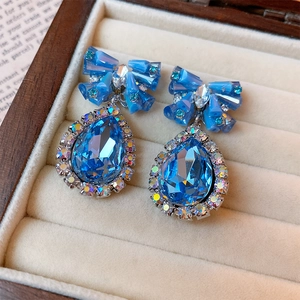 Detail of silver drop earrings with blue crystal bow and water drop rhinestones