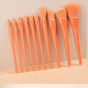 Detail of 10 orange candy-colored makeup brushes with soft synthetic bristles and handles