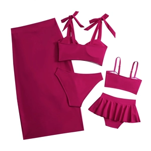 Flat lay of magenta family bikini set featuring ruffled skirts and bow-tie tops