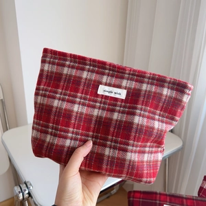 Gros plan d'une trousse à maquillage en laine à carreaux rouges avec étiquette en tissu