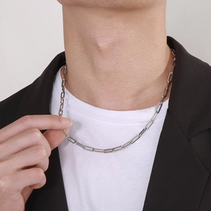 Close-up of a silver stainless steel paperclip chain necklace on a male model outfit