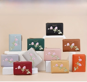 Close-up of assorted color leather wallets featuring delicate rose flower embroidery