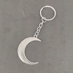 Silver vintage sun and moon keychain with crescent pendant on a grey textured surface