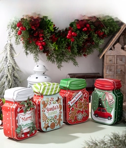 Detailed view of four festive Christmas tin jars featuring gingerbread and tree motifs