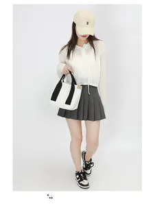 Detail of a minimalist cream canvas tote bag with black straps worn by a model